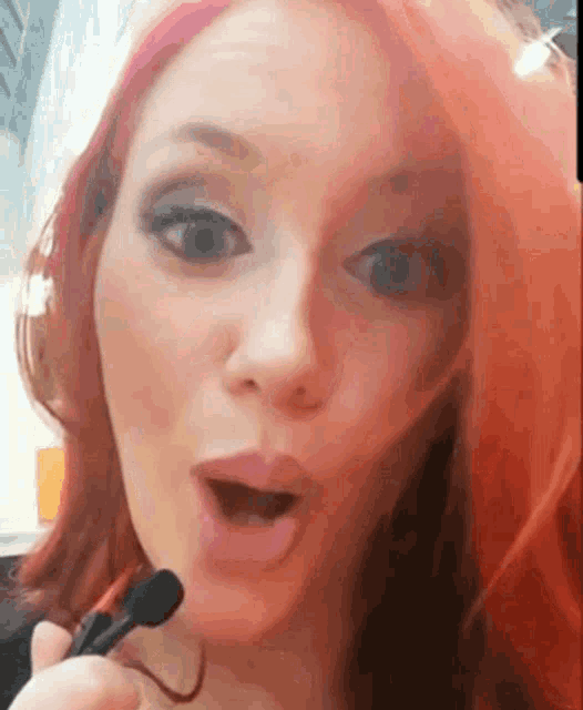 a woman with red hair is holding a microphone to her face
