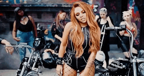 a woman with red hair is standing in front of a harley davidson motorcycle .