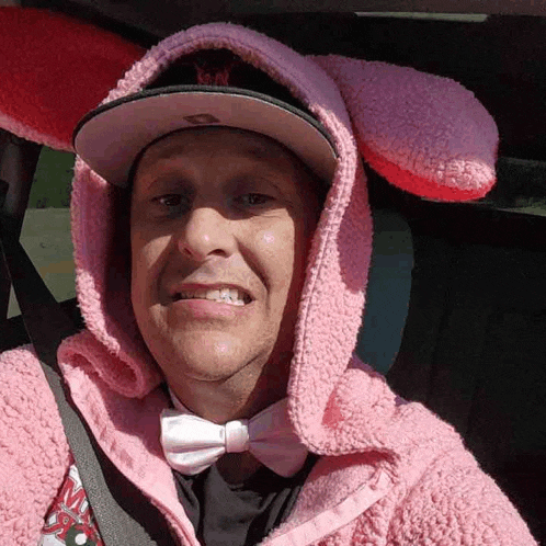 a man wearing a pink jacket and bunny ears is smiling