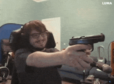 a man is holding a gun in front of a microphone while wearing headphones and glasses .