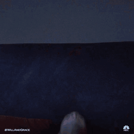 a man in a white shirt is making a funny face while laying on a bed .