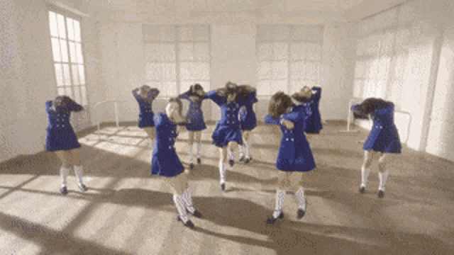 a group of girls in blue dresses and white socks are dancing in a room