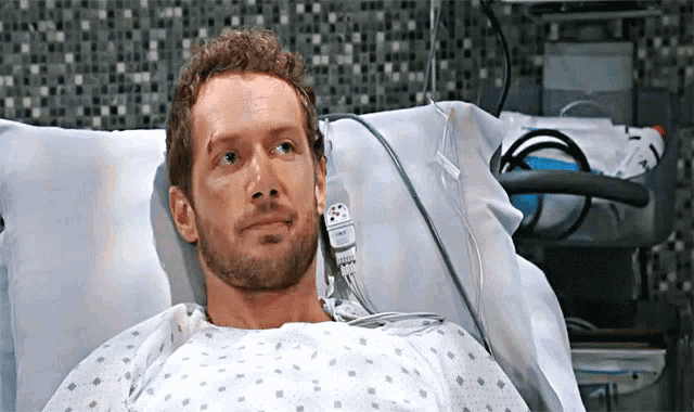 a man is laying in a hospital bed with a needle in his nose