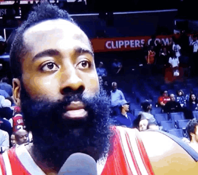 a man with a beard stands in front of a clippers sign