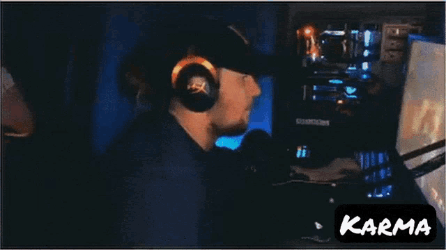 a man wearing headphones and a hat stands in front of a computer and the word karma is on the bottom