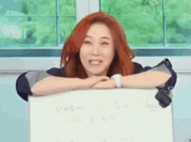 a woman with red hair is holding a sign that says i love you