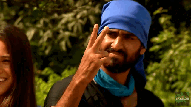 a man wearing a blue bandana and a black shirt with the word exatlon on the bottom