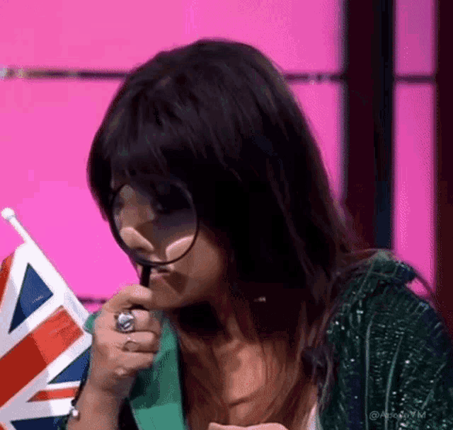 a woman is holding a british flag and using a magnifying glass to look at it .