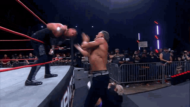 two men are wrestling in a ring with a sign that says no smoking on it