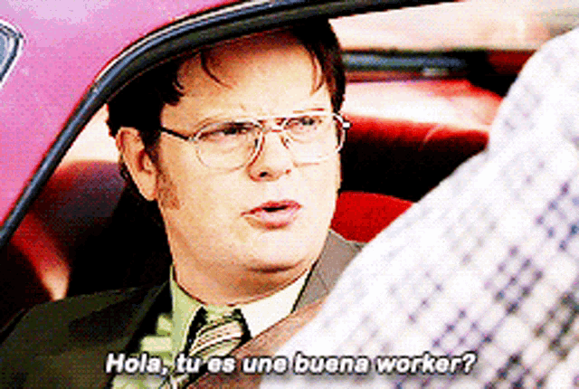 a man in a suit and tie is sitting in a car talking to another man and says hola tu es une buena worker