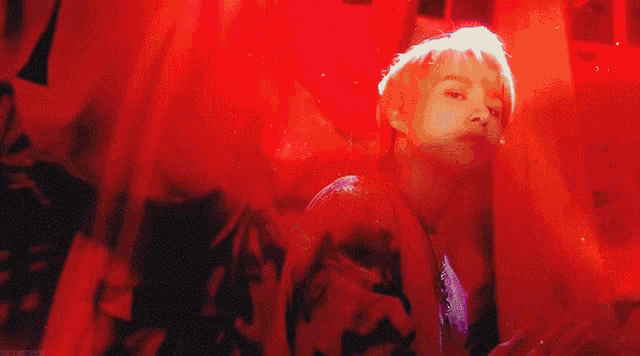 a man is standing in front of a red background in a dark room .