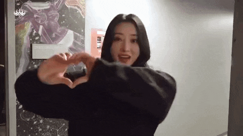 a woman is making a heart shape with her hands in a hallway .