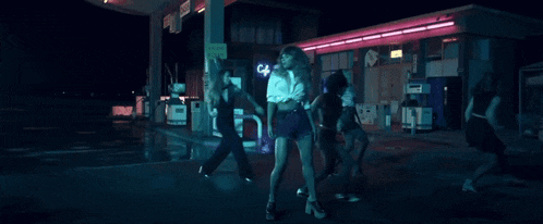 a group of women are dancing outside of a gas station