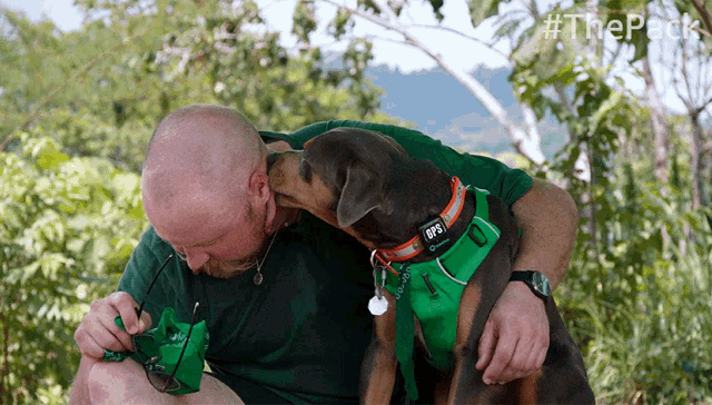 a man kisses a dog wearing a green harness with the letters gps on it