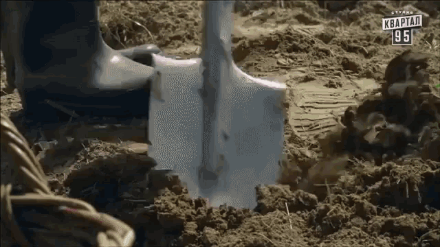 a person is digging in the dirt with a shovel and a sign that says kwartan 961