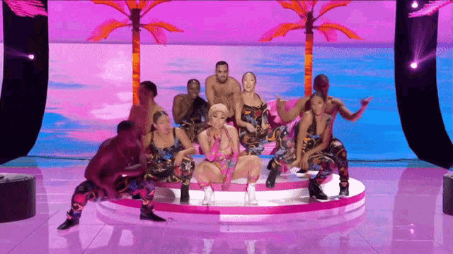 a group of people are dancing on a stage in front of a palm tree