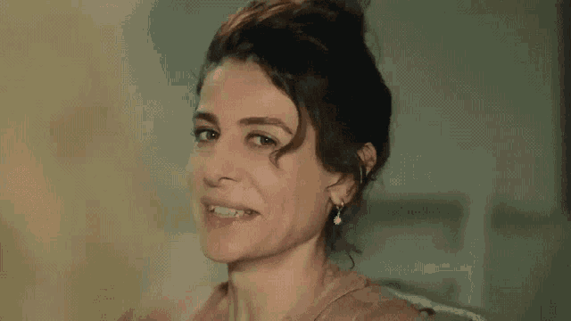 a woman is sitting on a couch smiling and looking at the camera .