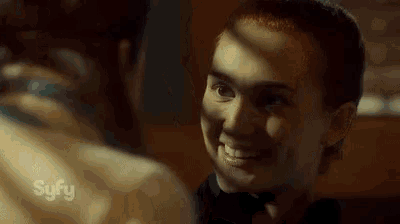 a man and a woman are looking at each other in a dark room and smiling .