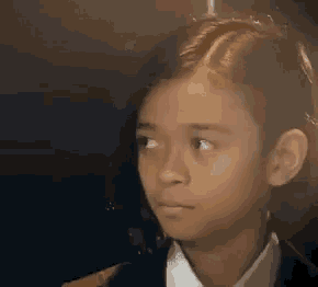a young boy in a suit and tie is looking at the camera .