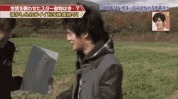 a man is standing in a field holding a piece of paper with chinese writing on it .