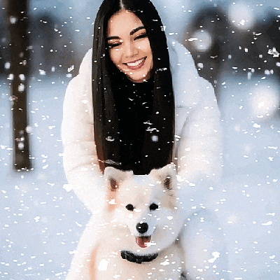a woman in a white fur coat is holding a small white dog in the snow