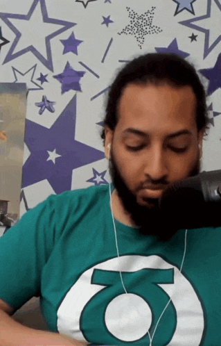 a man with a beard wearing a green shirt with the letter o on it
