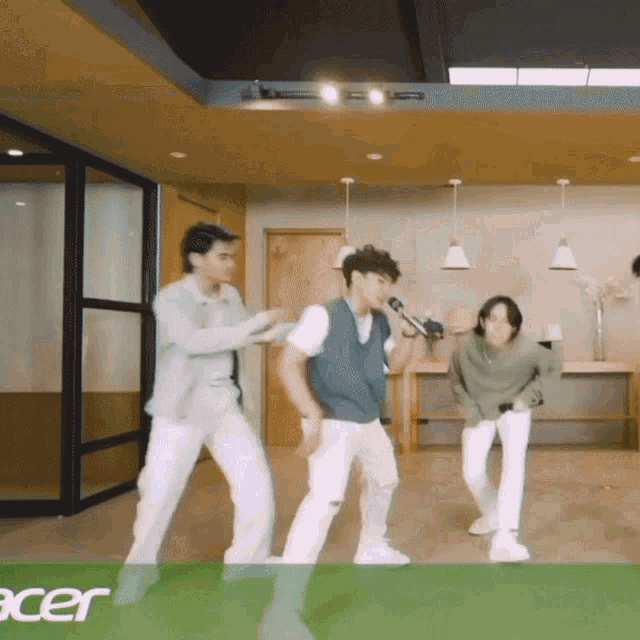 a group of young men are dancing in a room with the word acer in the corner