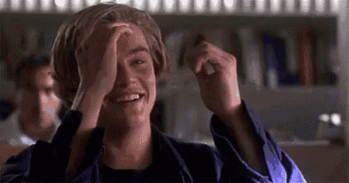 a young man is covering his face with his hands while smiling .
