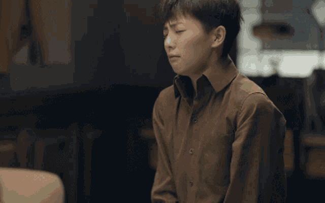 a man in a brown shirt with chinese writing on the screen