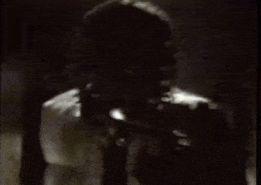 a black and white photo of a man with dreadlocks in a room .