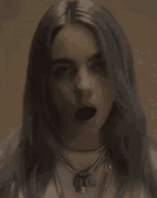 billie eilish is holding a spider in her mouth .