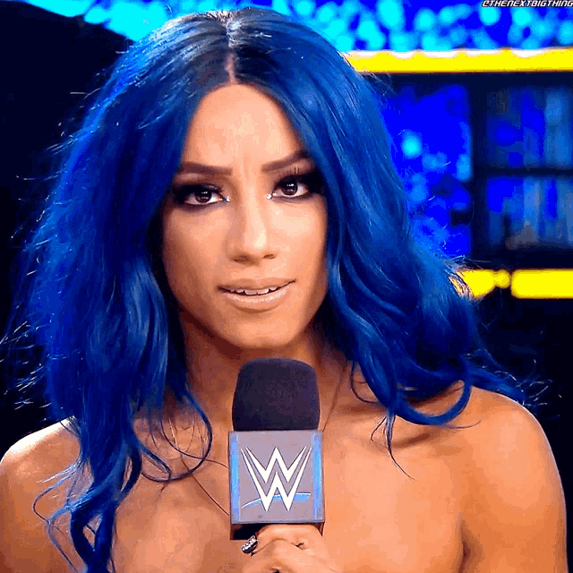 a woman with blue hair is holding a microphone that says wwe on it