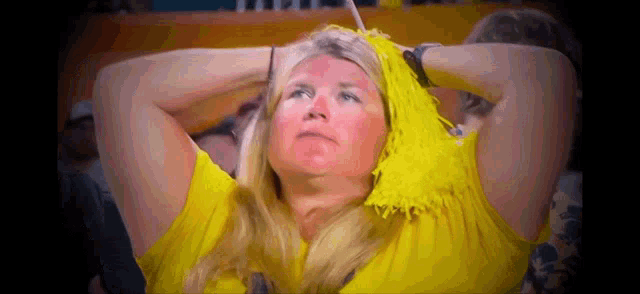 a woman with yellow pom poms on her head is watching a game