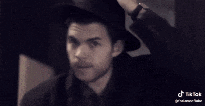 a man wearing a black hat is making a funny face with his hand
