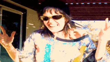a woman wearing sunglasses and a black hat is making a funny face
