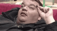 a fat man is laying on a couch and looking at something .