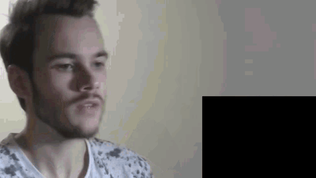 a man with a beard is wearing a white shirt with black spots on it .