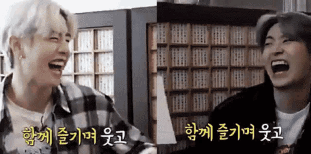 two men are laughing in front of a bookshelf in a library