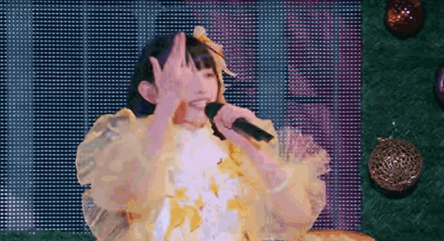 a girl singing into a microphone in front of a screen