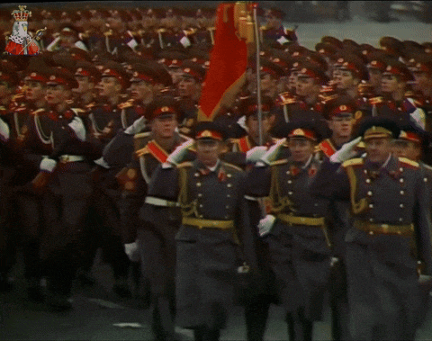 a group of soldiers marching in a parade with a crown on the bottom right