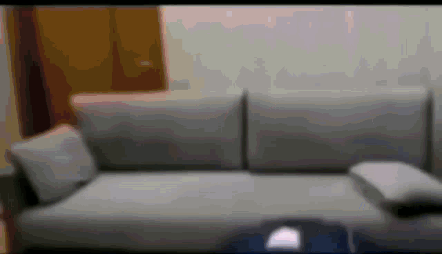 a gray couch is sitting in a living room with a table in front of it .