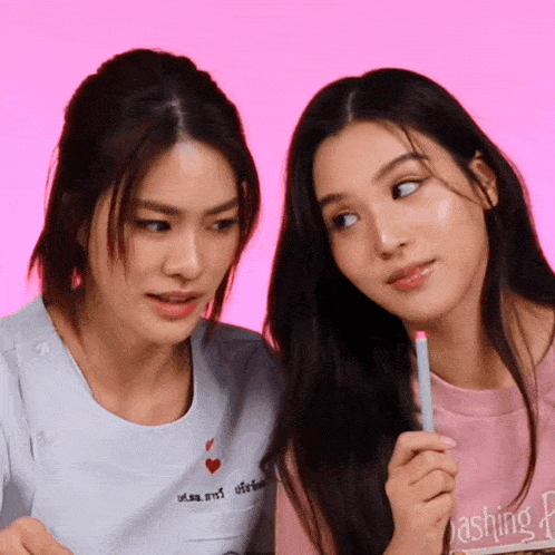 a woman holding a pen next to another woman who is wearing a shirt that says rashing