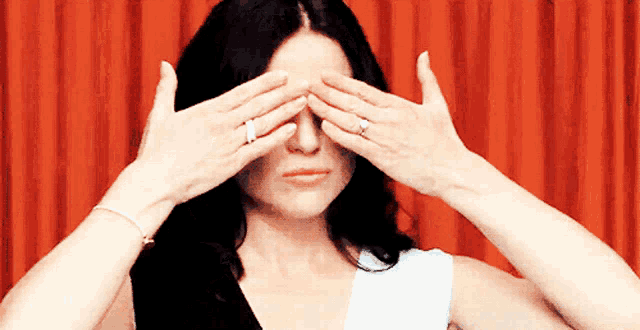 a woman with a ring on her finger covering her eyes with her hands