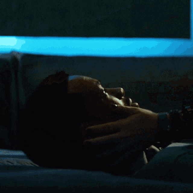 a person is touching another person 's face with a blue light behind them