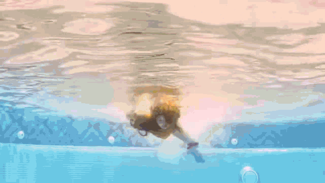 a person is swimming in a pool with a gummy bear in their hand .