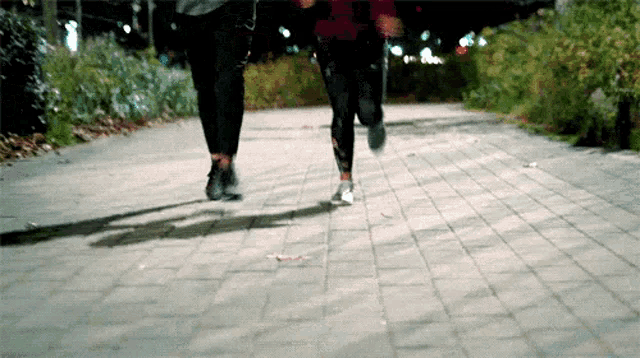 a man and a woman are running down a brick path .