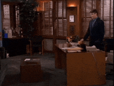 a man in a suit and tie is standing in front of a desk