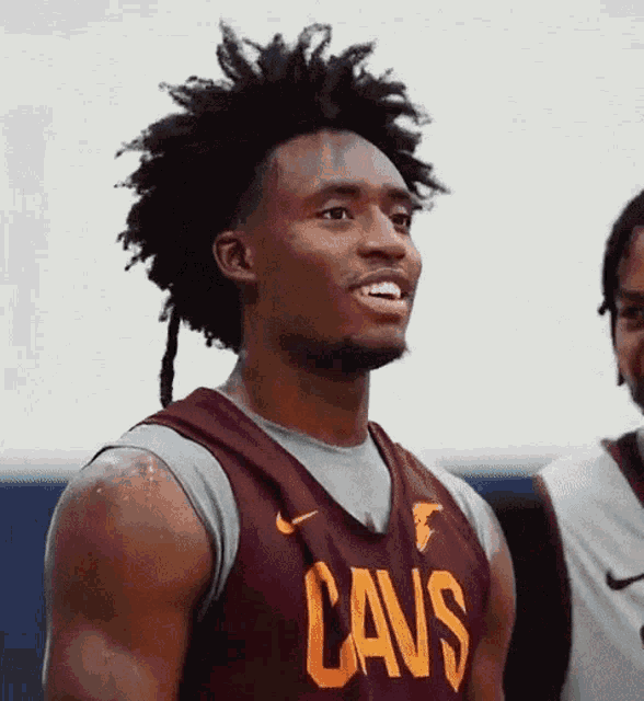 a man wearing a cavs jersey smiles while standing next to another man