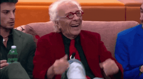 an elderly man in a red jacket and tie is laughing