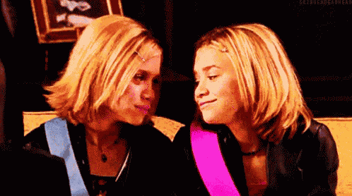 two blonde women are looking at each other and smiling .